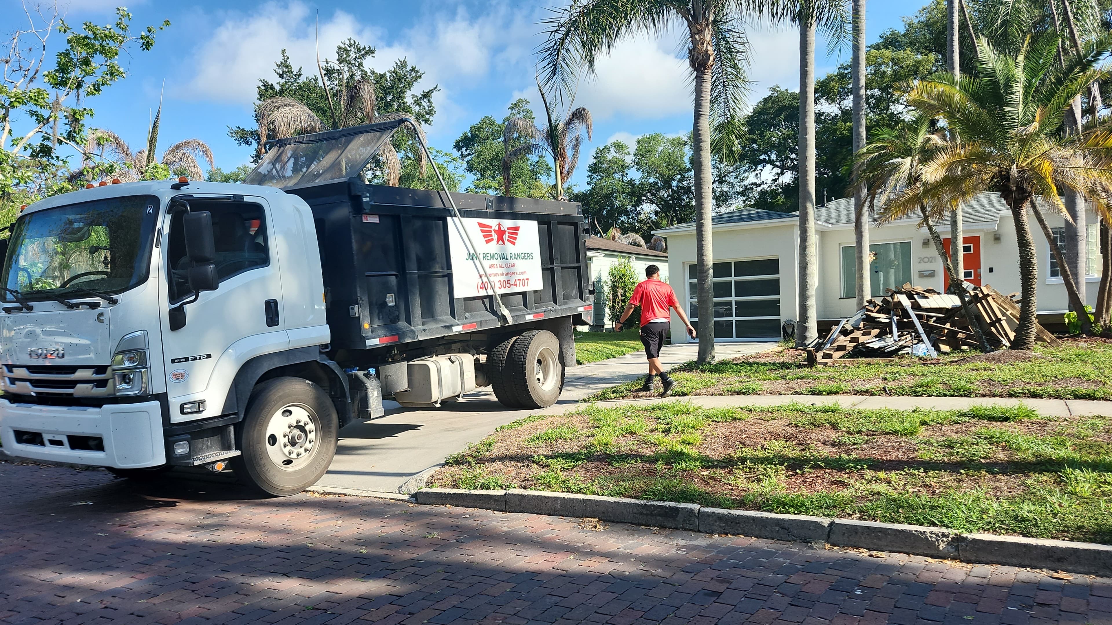 During: Junk Removal Rangers Isuzu FTR truck arrives on brick street for deck debris removal in Orlando